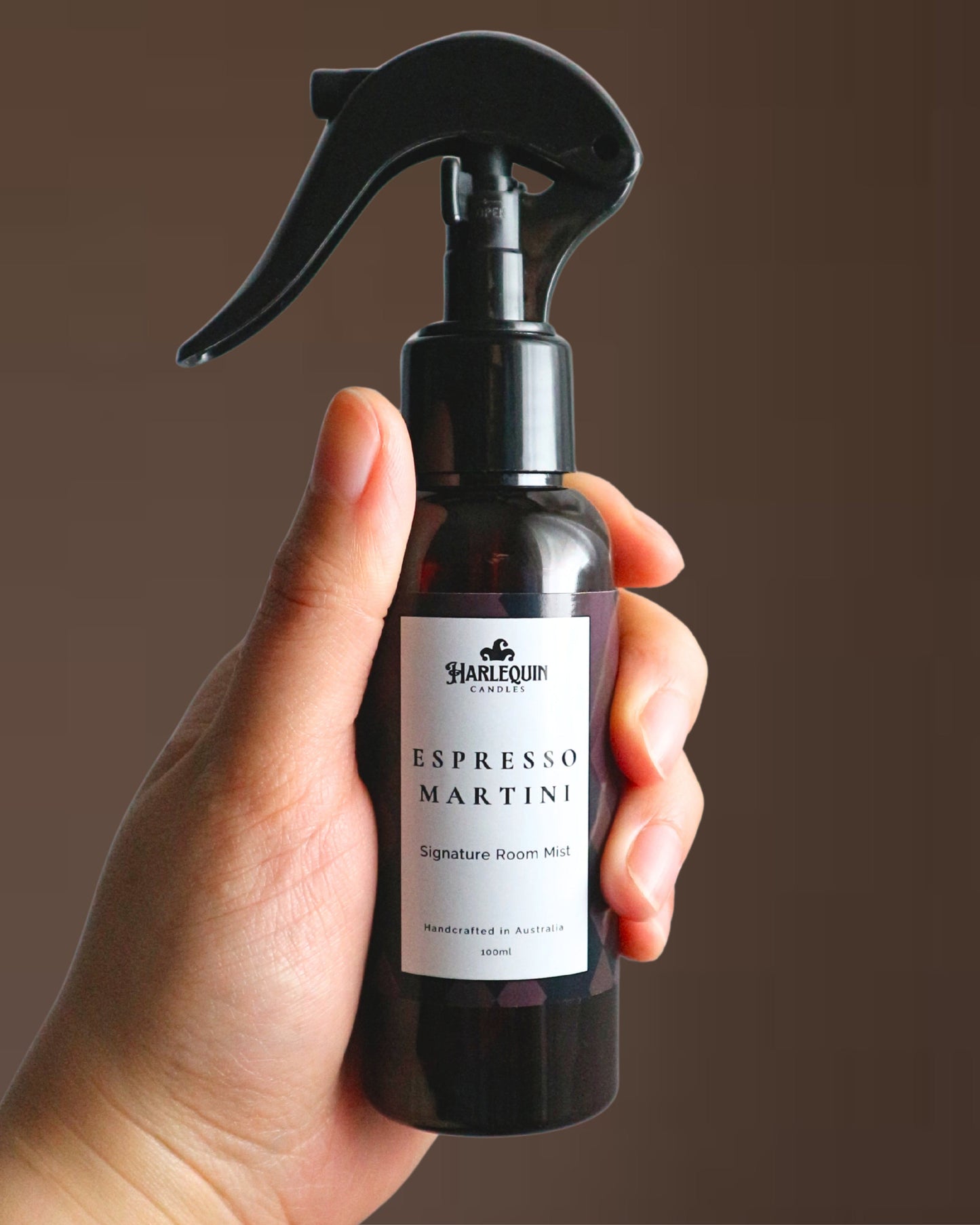 A Harlequin Candles Espresso Martini Signature Room Mist in an amber spray bottle with a black trigger cap, placed against a clean, light grey background. The label clearly shows 'Harlequin Candles', 'Espresso Martini', 'Signature Room Mist', and 'Handcrafted in Australia', highlighting this invigorating Australian-made home spray.