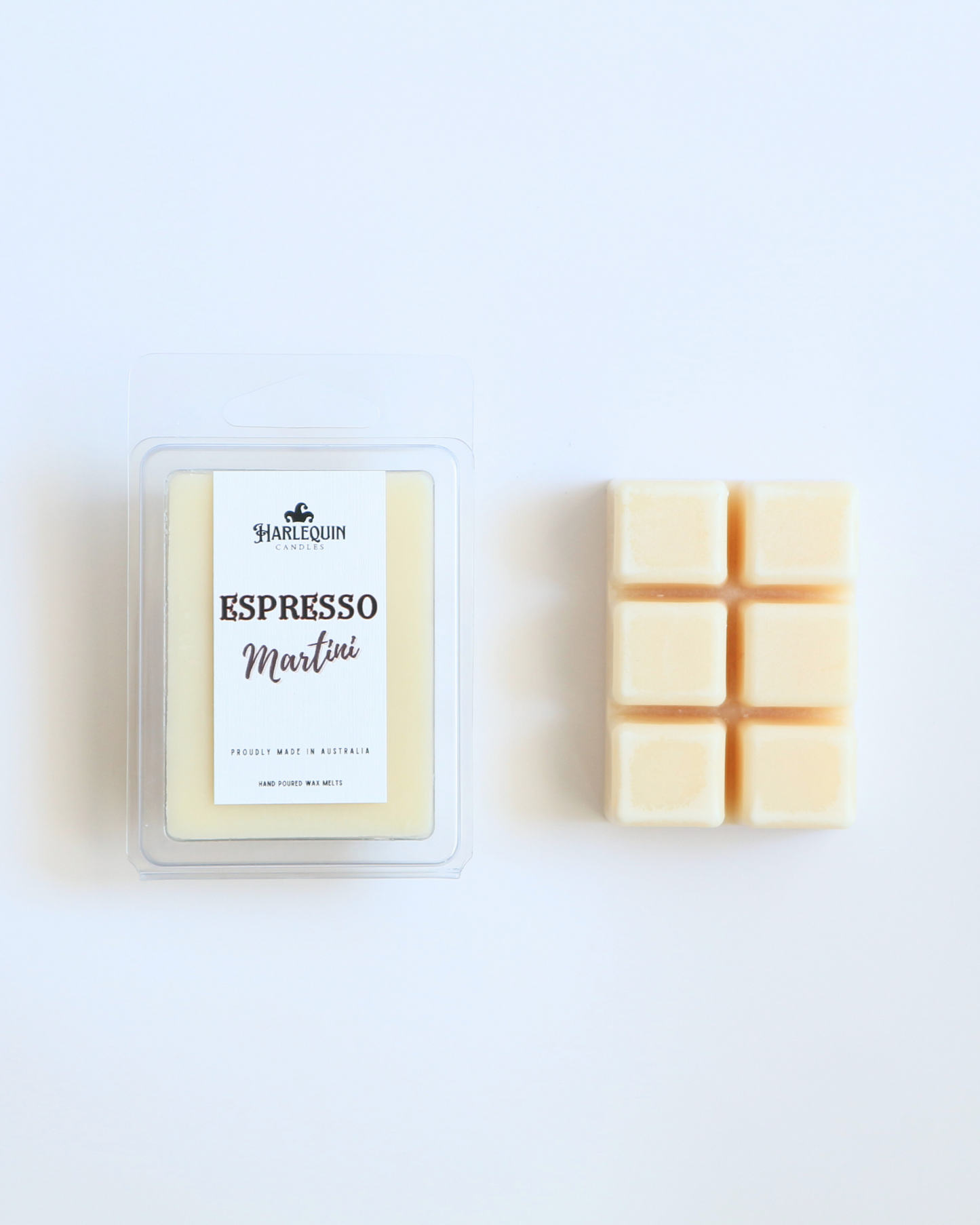 Harlequin Candles Espresso Martini soy wax melts, displayed in clear plastic clamshell packaging with the brand label. The label reads 'ESPRESSO Martini' and 'PROUDLY MADE IN AUSTRALIA HAND POURED WAX MELTS'. Several individual wax melt cubes are scattered on a light wooden cutting board, showcasing the coffee-scented home fragrance product and its local origin.