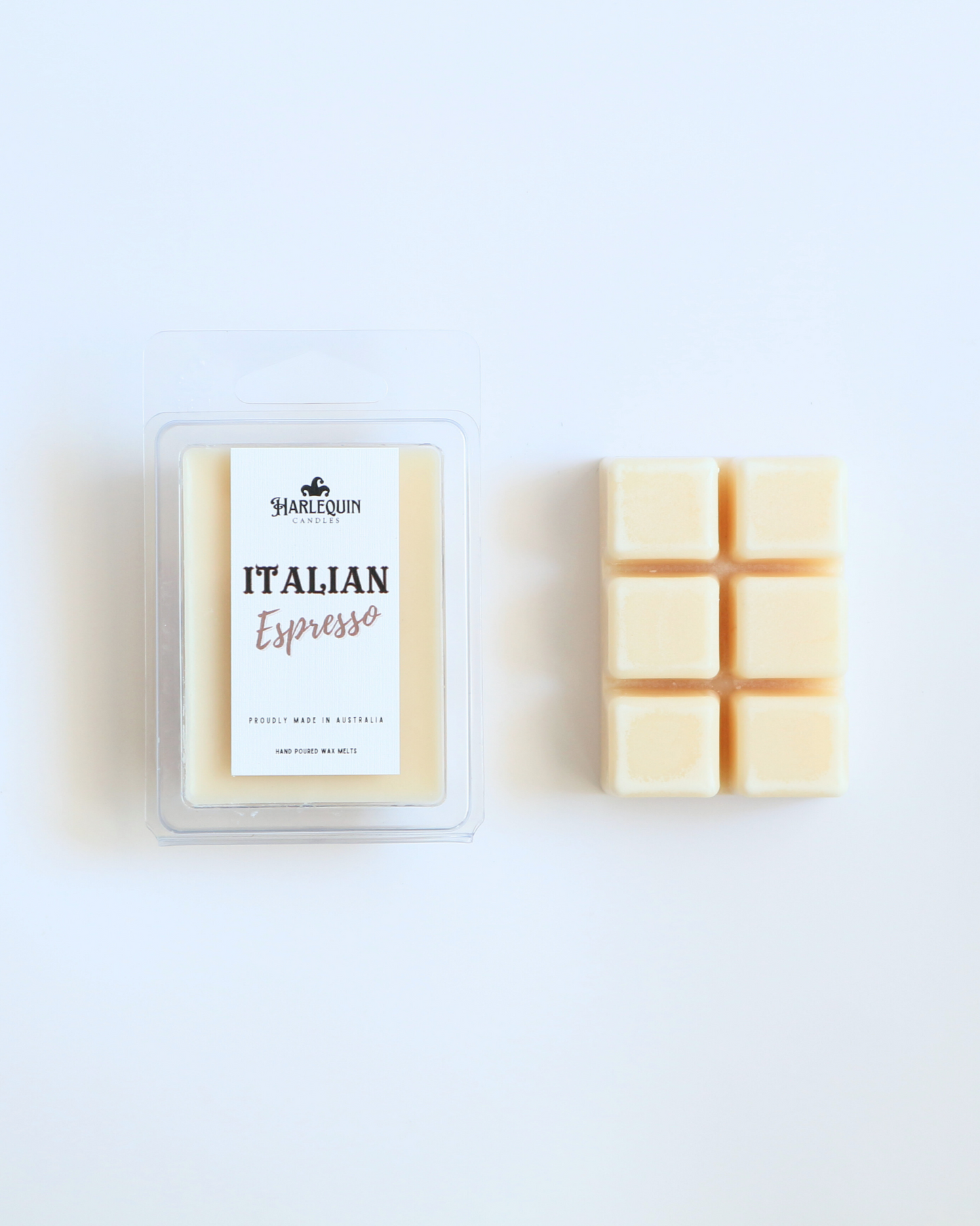 Harlequin Candles Italian Espresso soy wax melts, displayed in clear plastic clamshell packaging with the brand label. The label reads 'ITALIAN Espresso' and 'PROUDLY MADE IN AUSTRALIA HAND POURED WAX MELTS'. Several individual wax melt cubes are scattered on a light wooden cutting board, showcasing the coffee-scented home fragrance product and its local origin.