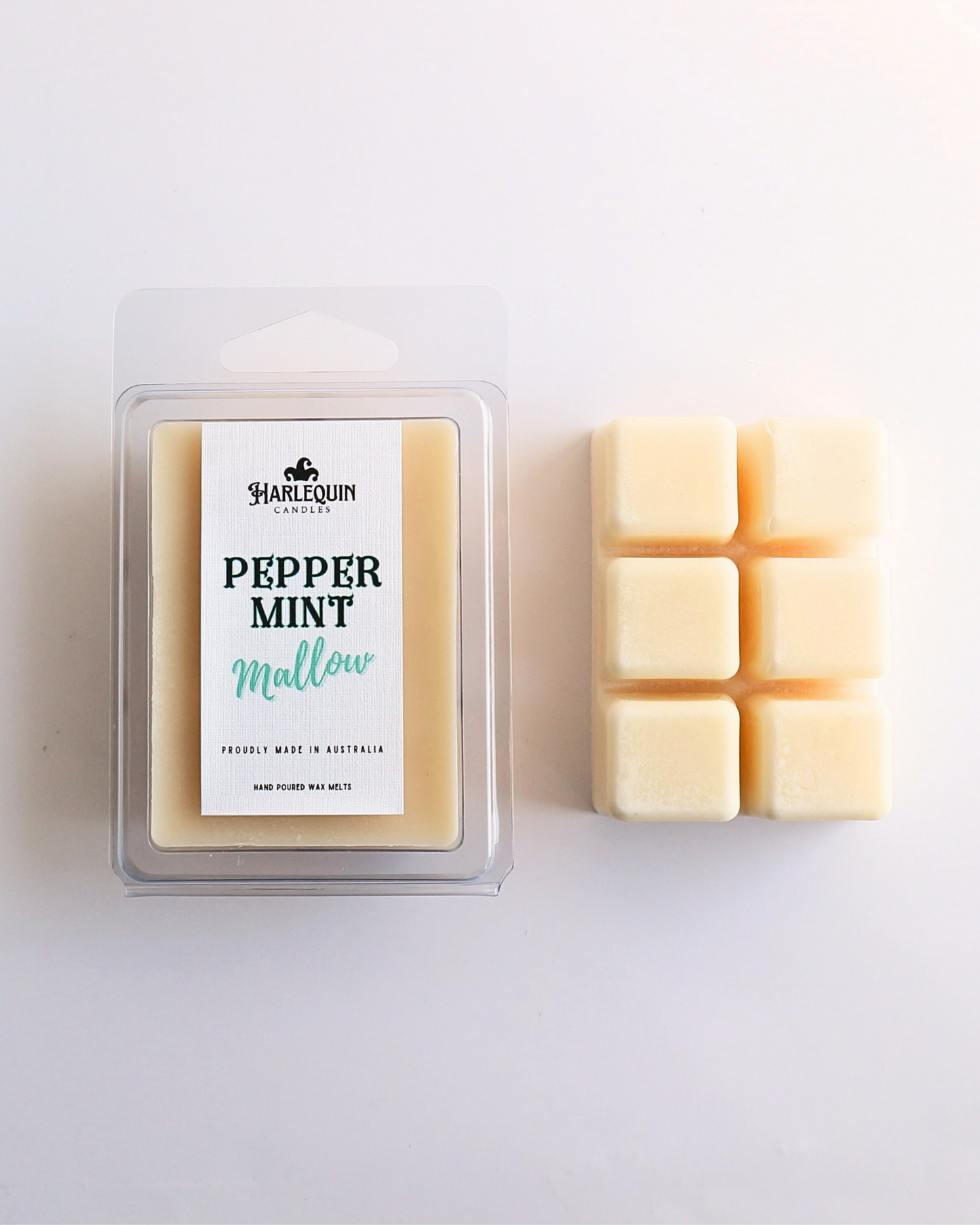 Harlequin Candles Peppermint Mallow soy wax melts, displayed in clear plastic clamshell packaging with the brand label. The label reads 'PEPPERMINT Mallow' and 'PROUDLY MADE IN AUSTRALIA HAND POURED WAX MELTS'. Several individual wax melt cubes are scattered on a light wooden cutting board, showcasing the product and its local origin.