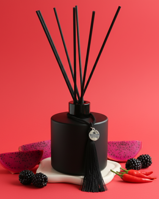 An Australian made Harlequin Candles reed diffuser with an exotic and spicy home scent called Fruit & Fire.The product is shown on a red background with dragonfruit, blackberries, and chili peppers and chipotle.