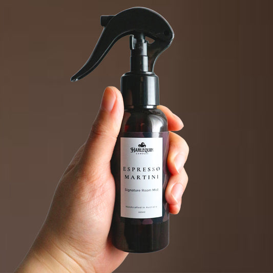 A Harlequin Candles Espresso Martini Signature Room Mist in an amber spray bottle with a black trigger cap, placed against a clean, light grey background. The label clearly shows 'Harlequin Candles', 'Espresso Martini', 'Signature Room Mist', and 'Handcrafted in Australia', highlighting this invigorating Australian-made home spray.