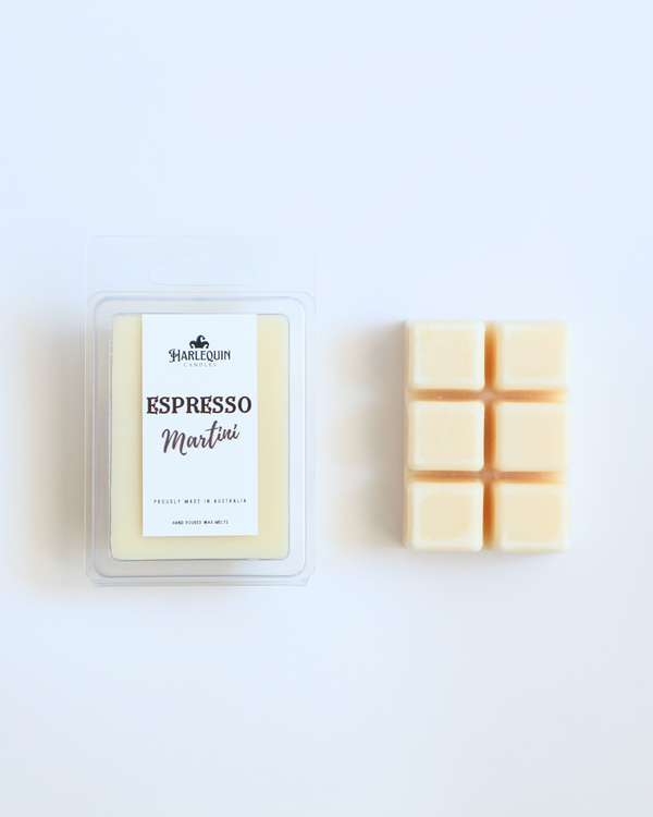 Harlequin Candles Espresso Martini soy wax melts, displayed in clear plastic clamshell packaging with the brand label. The label reads 'ESPRESSO Martini' and 'PROUDLY MADE IN AUSTRALIA HAND POURED WAX MELTS'. Several individual wax melt cubes are scattered on a light wooden cutting board, showcasing the coffee-scented home fragrance product and its local origin.