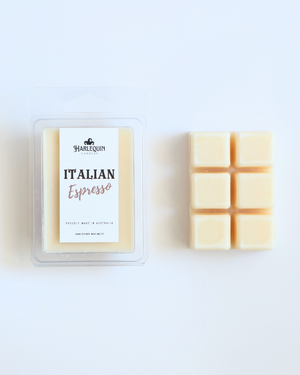 Harlequin Candles Italian Espresso soy wax melts, displayed in clear plastic clamshell packaging with the brand label. The label reads 'ITALIAN Espresso' and 'PROUDLY MADE IN AUSTRALIA HAND POURED WAX MELTS'. Several individual wax melt cubes are scattered on a light wooden cutting board, showcasing the coffee-scented home fragrance product and its local origin.