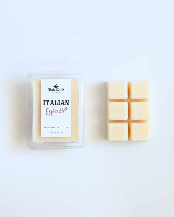 Harlequin Candles Italian Espresso soy wax melts, displayed in clear plastic clamshell packaging with the brand label. The label reads 'ITALIAN Espresso' and 'PROUDLY MADE IN AUSTRALIA HAND POURED WAX MELTS'. Several individual wax melt cubes are scattered on a light wooden cutting board, showcasing the coffee-scented home fragrance product and its local origin.