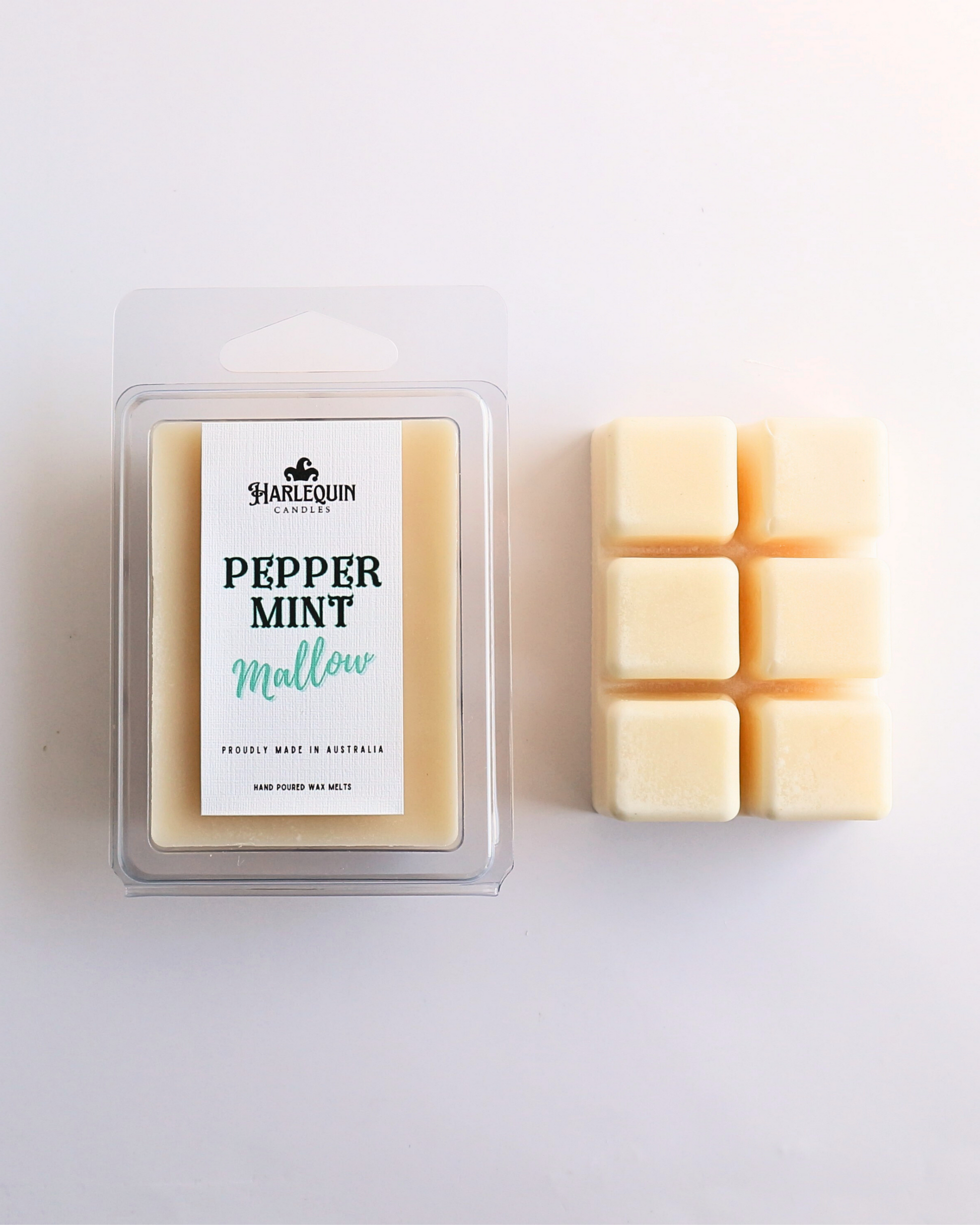 Harlequin Candles Peppermint Mallow soy wax melts, displayed in clear plastic clamshell packaging with the brand label. The label reads 'PEPPERMINT Mallow' and 'PROUDLY MADE IN AUSTRALIA HAND POURED WAX MELTS'. Several individual wax melt cubes are scattered on a light wooden cutting board, showcasing the product and its local origin.