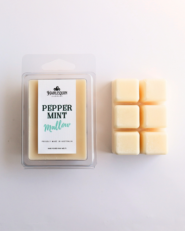 Harlequin Candles Peppermint Mallow soy wax melts, displayed in clear plastic clamshell packaging with the brand label. The label reads 'PEPPERMINT Mallow' and 'PROUDLY MADE IN AUSTRALIA HAND POURED WAX MELTS'. Several individual wax melt cubes are scattered on a light wooden cutting board, showcasing the product and its local origin.