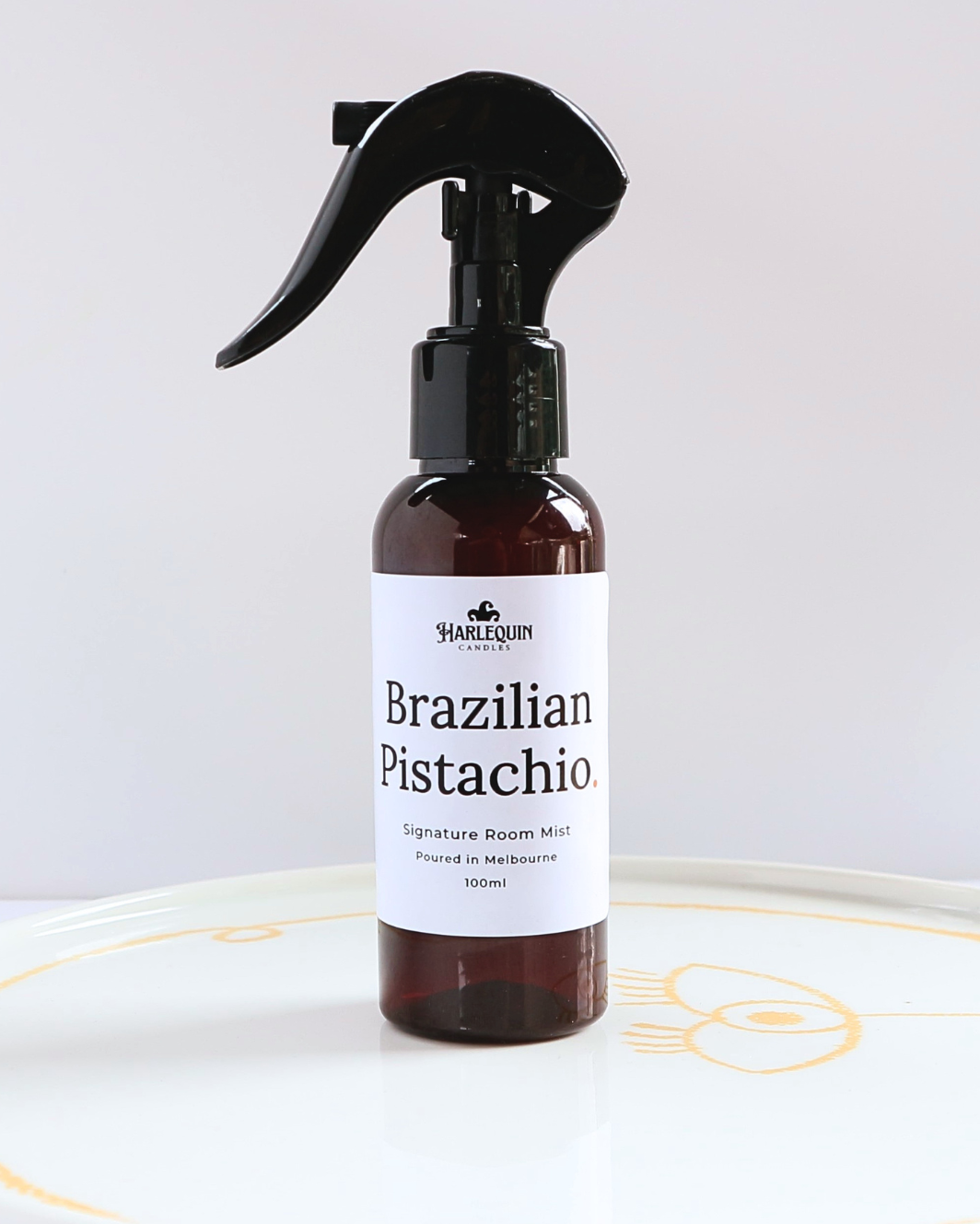 Harlequin Candles Brazilian Pistachio Bum Bum Type fragrance 100ml signature room mist in a premium amber spray bottle on a minimalist white ceramic tray, handmade in Melbourne Australia.