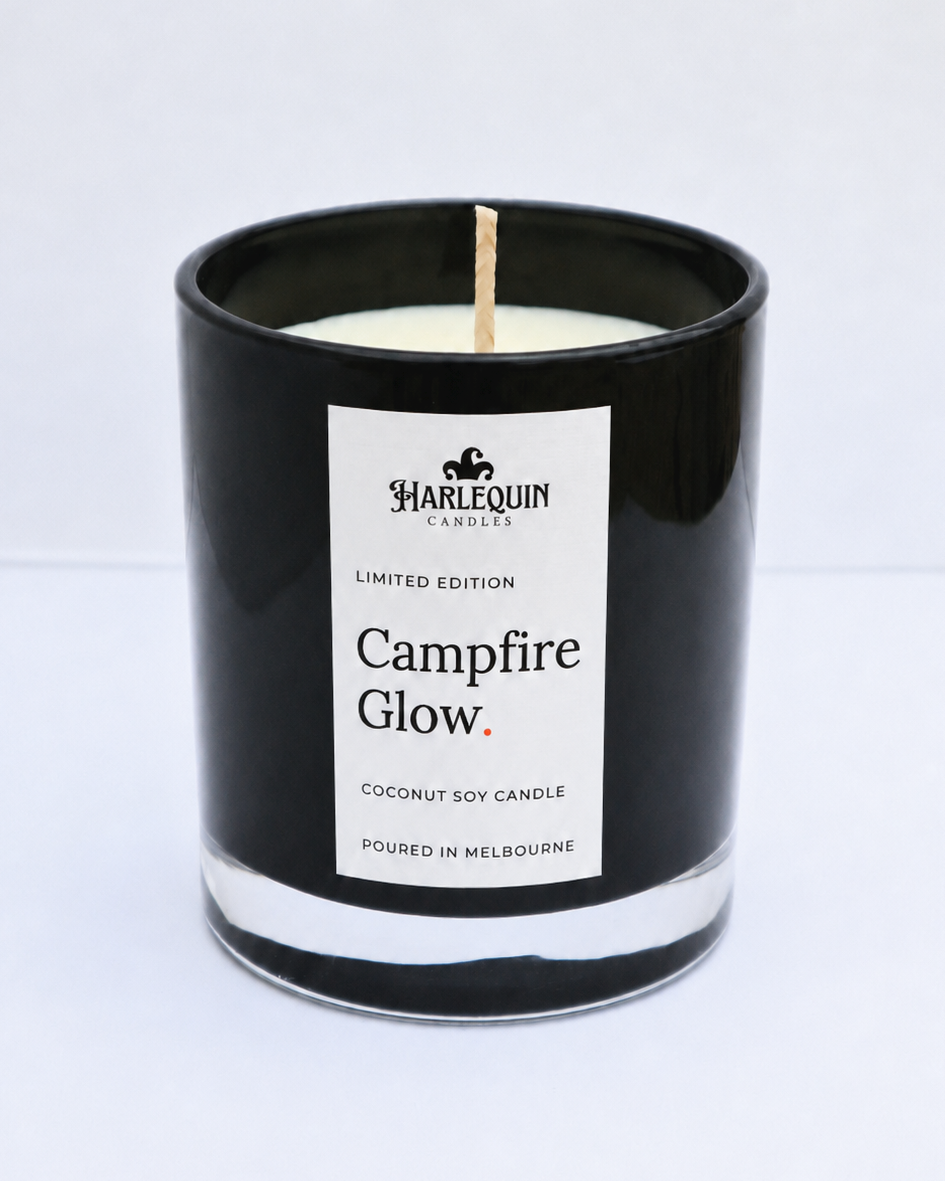 Campfire Glow smoky wood coconut soy candle in a black glass jar with cotton wick and white linen label, hand-poured in Melbourne.