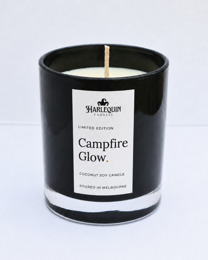 Campfire Glow smoky wood coconut soy candle in a black glass jar with cotton wick and white linen label, hand-poured in Melbourne.