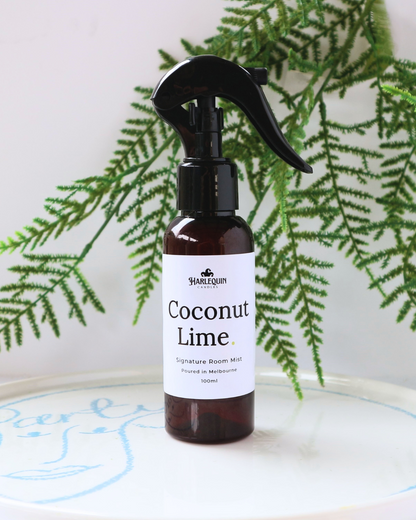 Tropical Coconut Lime luxury home fragrance spray styled with green fern leaves on a white designer tray, refreshing citrus room deodorizer by Harlequin Candles.