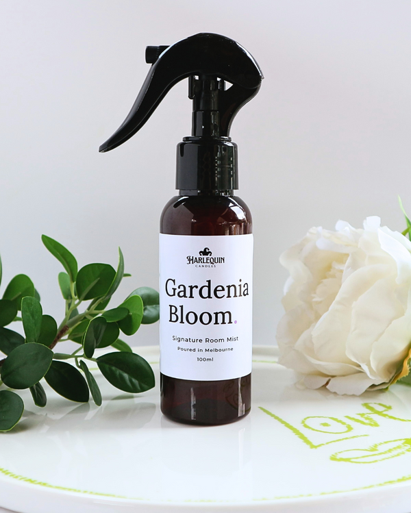 Luxury Gardenia Bloom home fragrance spray styled with fresh green leaves and white gardenia flowers on a designer ceramic tray, sophisticated floral room deodorizer by Harlequin Candles.