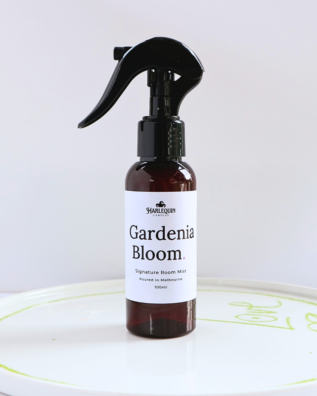 Harlequin Candles Gardenia Bloom 100ml signature room mist in a premium amber spray bottle on a minimalist white ceramic tray, hand-poured in Melbourne Australia.
