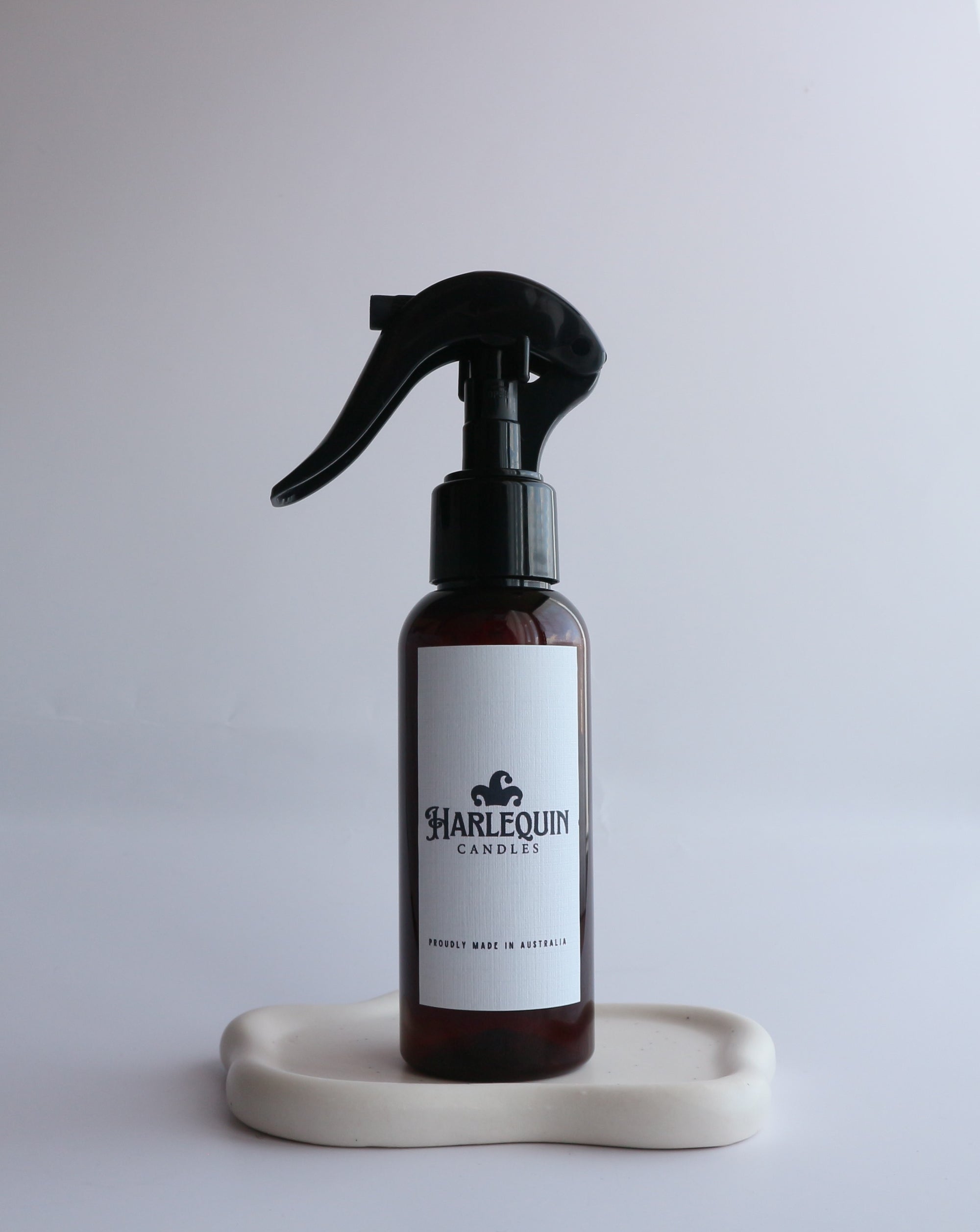 Luxury handmade room spray by Harlequin Candles, an Australian made home fragrance product. This amber trigger spray bottle is styled on a minimalist tray, making it perfect for gifting or bringing personality to your home.