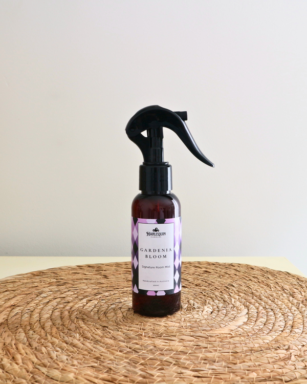 Handcrafted Australian Gardenia room mist by Harlequin Candles, presented in a luxe amber spray bottle on a textured woven mat against a soft neutral background.