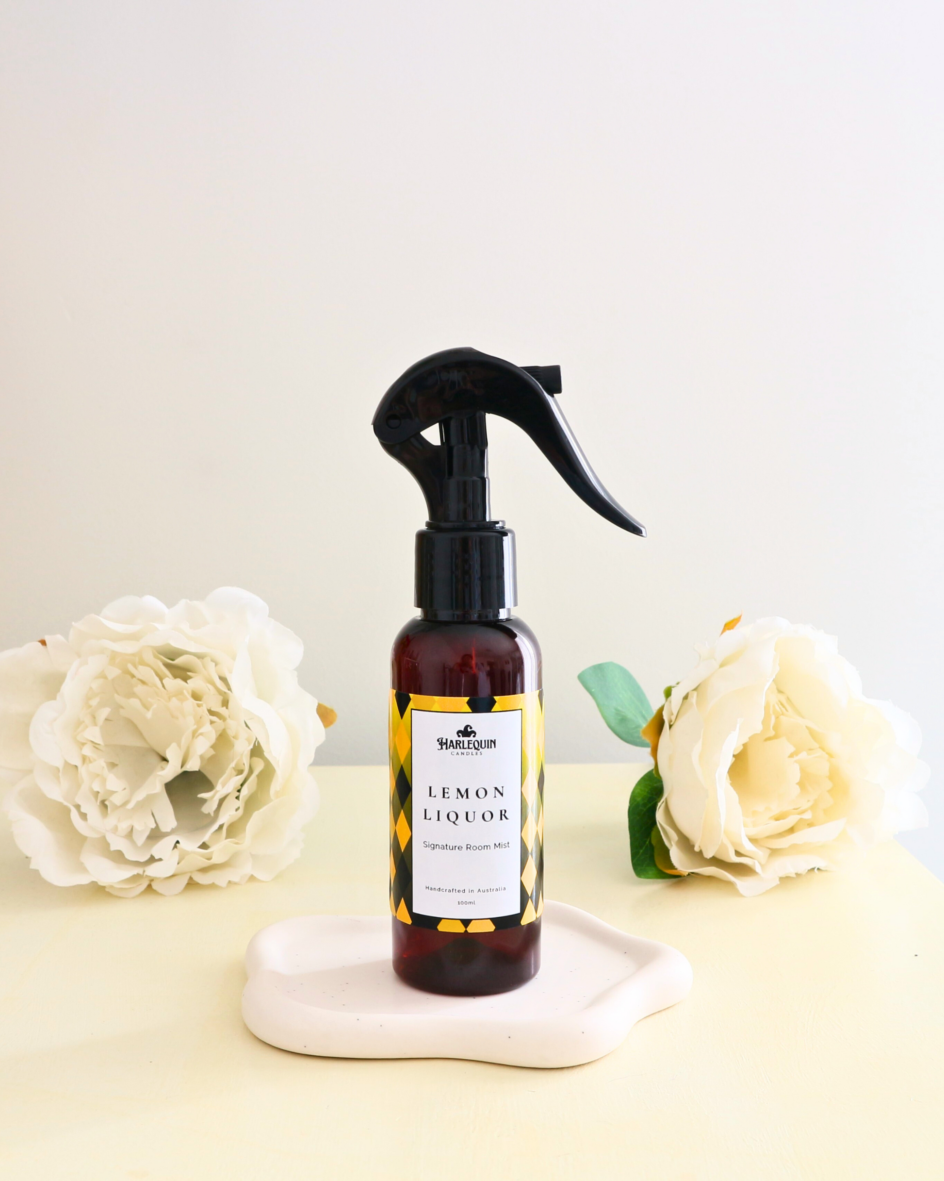 Handcrafted Australian Limoncello room mist by Harlequin Candles, presented in a luxe amber spray bottle on a textured woven mat against a soft neutral background.