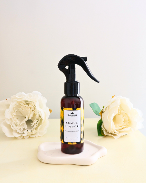 Handcrafted Australian Limoncello room mist by Harlequin Candles, presented in a luxe amber spray bottle on a textured woven mat against a soft neutral background.