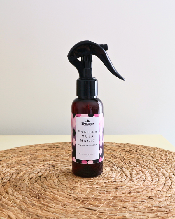 Handcrafted Australian Vanilla Musk Marshmallow room mist by Harlequin Candles, presented in a luxe amber spray bottle on a textured woven mat against a soft neutral background.