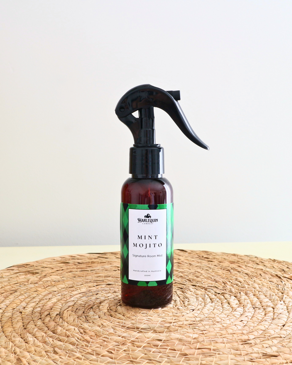 Handcrafted Australian Mint Mojito room mist by Harlequin Candles, presented in a luxe amber spray bottle on a textured woven mat against a soft neutral background.