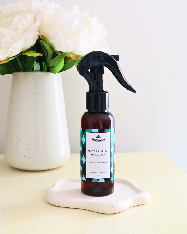 Handcrafted Australian Peppermint Marshamallow room mist by Harlequin Candles, presented in a luxe amber spray bottle on a textured woven mat against a soft neutral background.