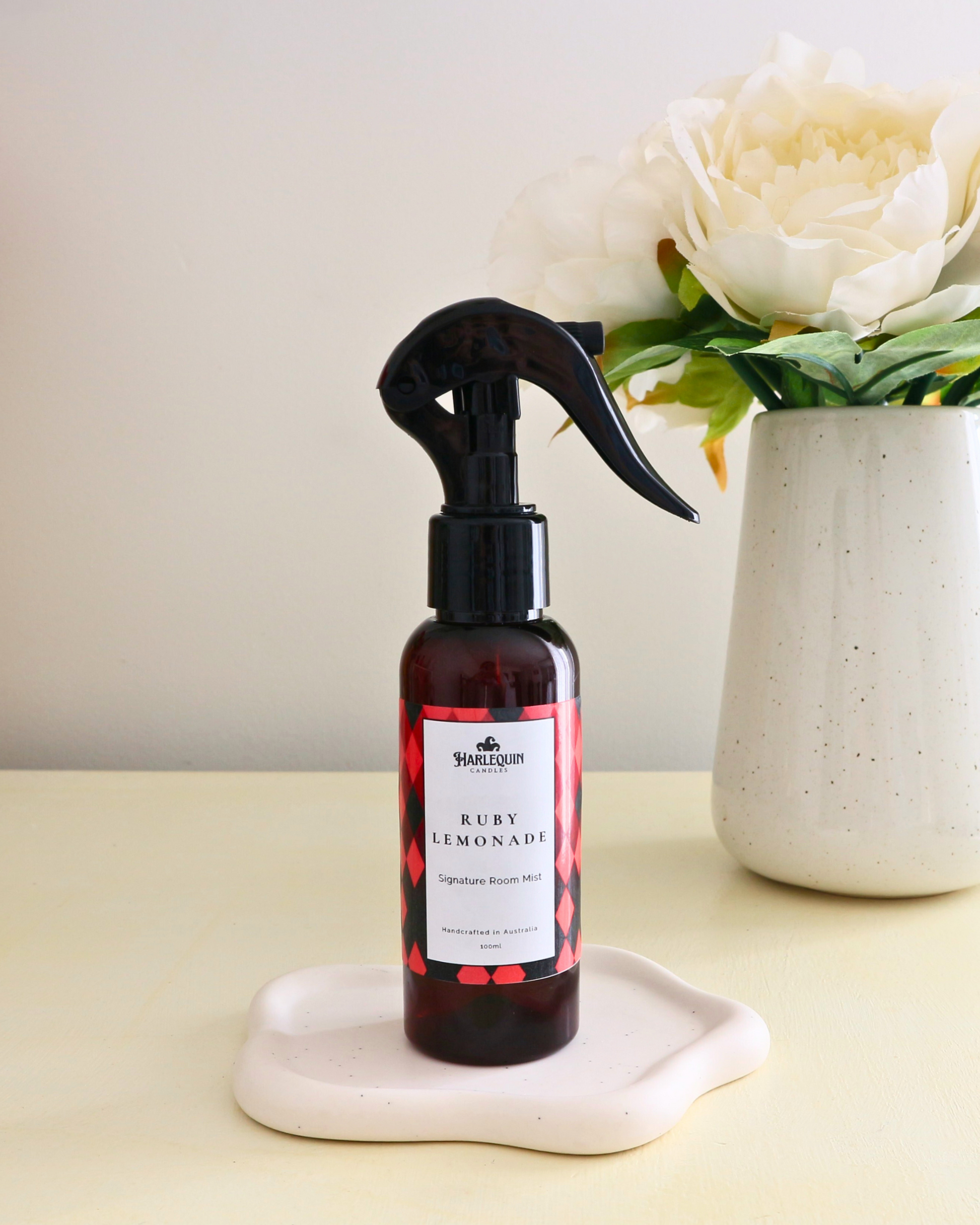
Handcrafted Australian Watermelon Lemonade room mist by Harlequin Candles, presented in a luxe amber spray bottle on a textured woven mat against a soft neutral background.