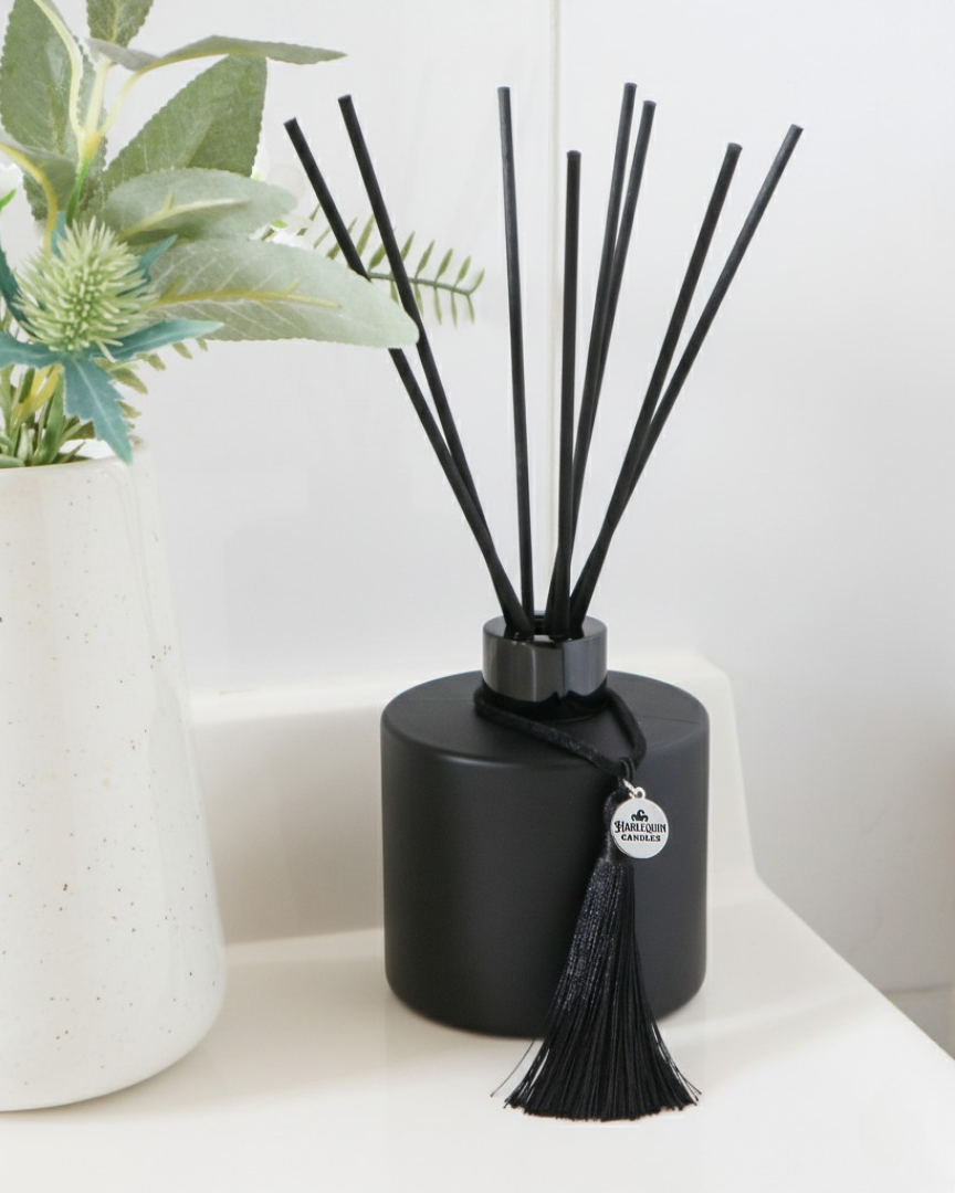 Hand-poured matte black reed diffuser by Harlequin Candles, handmade in Canberra, Australia, featuring black fibre reeds and a signature silver charm.