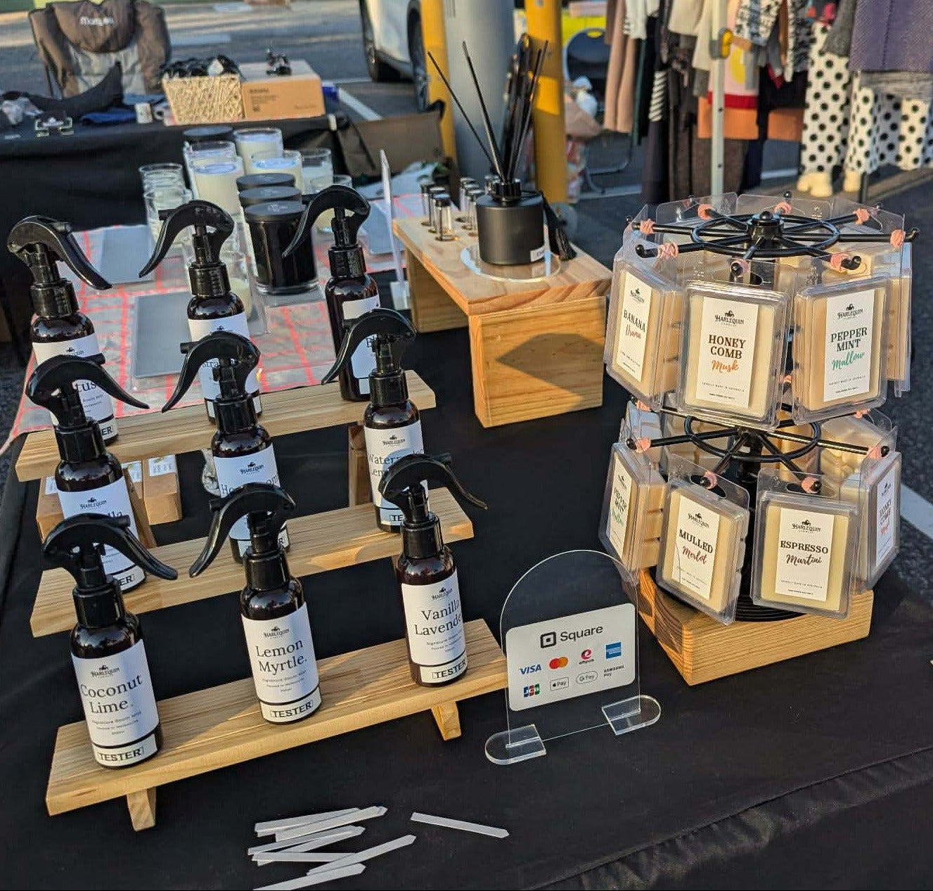 A close-up of the Harlequin Candles market stall display at Bentleigh Sunday Market, showcasing handmade soy wax melts, room mists, and reed diffusers made in Melbourne.