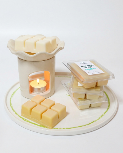 A close-up of a white wax melt warmer melting a natural soy wax cube next to a package of "Peppermint Mallow" melts. Handmade, high-scent load Australian wax melts.
