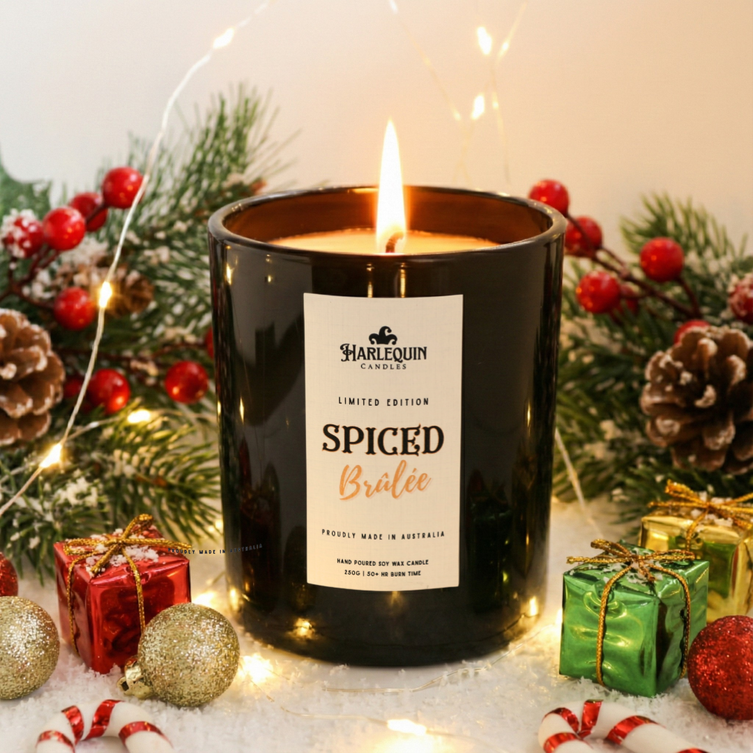 Harlequin Candles Spiced Brûlée limited edition hand-poured soy wax candle in a sleek black glass jar, glowing warmly against a simple festive backdrop. A luxury Australian-made home fragrance perfect for Christmas gifting.