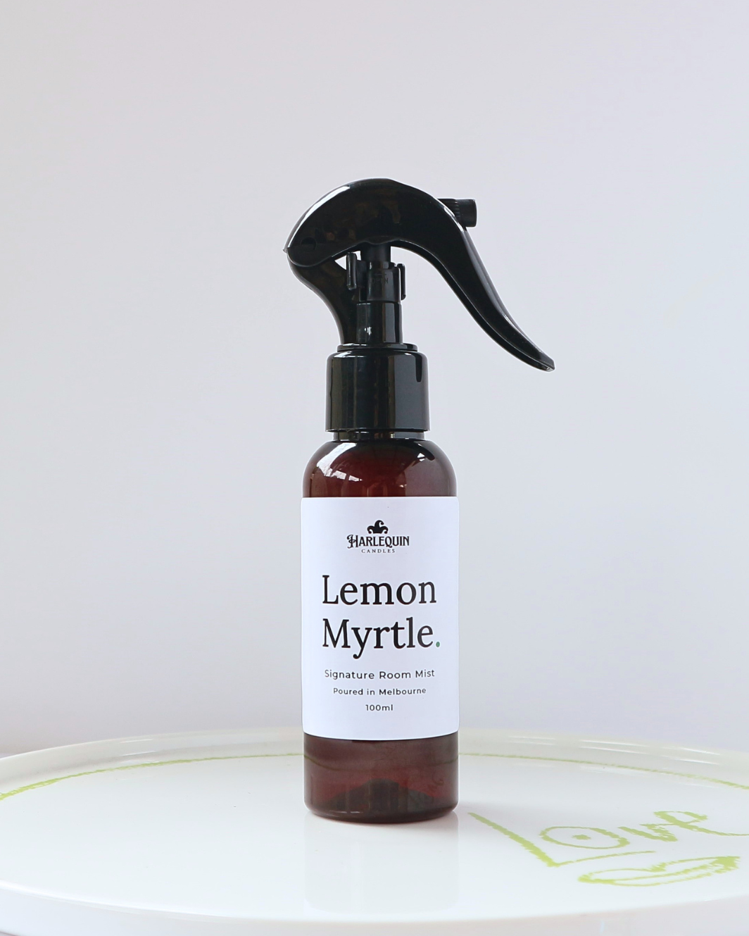 Harlequin Candles Lemon Myrtle 100ml signature room mist in a premium amber glass spray bottle on a minimalist white ceramic tray, hand-poured in Melbourne Australia.