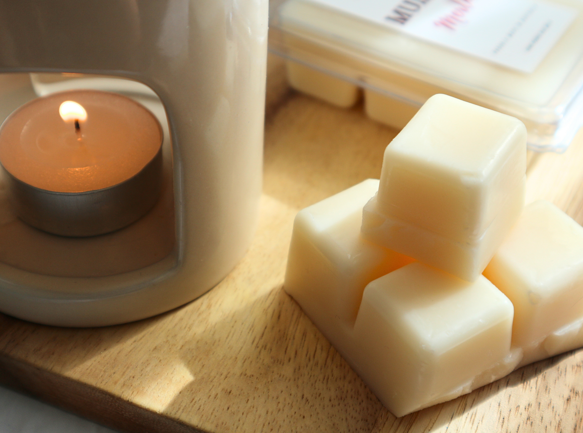 A stack of cream colored soy wax melts sitting next to a lit burner.  