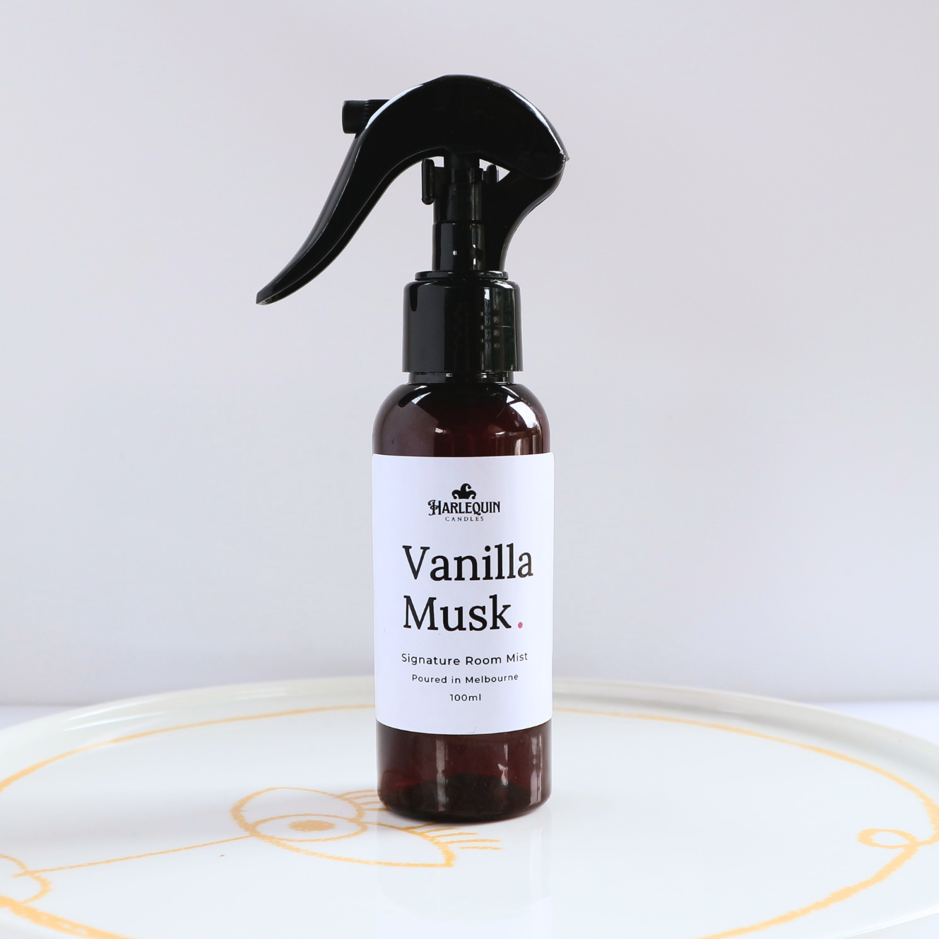Harlequin Candles Vanilla Musk 100ml signature room mist in a premium amber glass spray bottle on a minimalist white ceramic tray, handmade in Melbourne Australia.